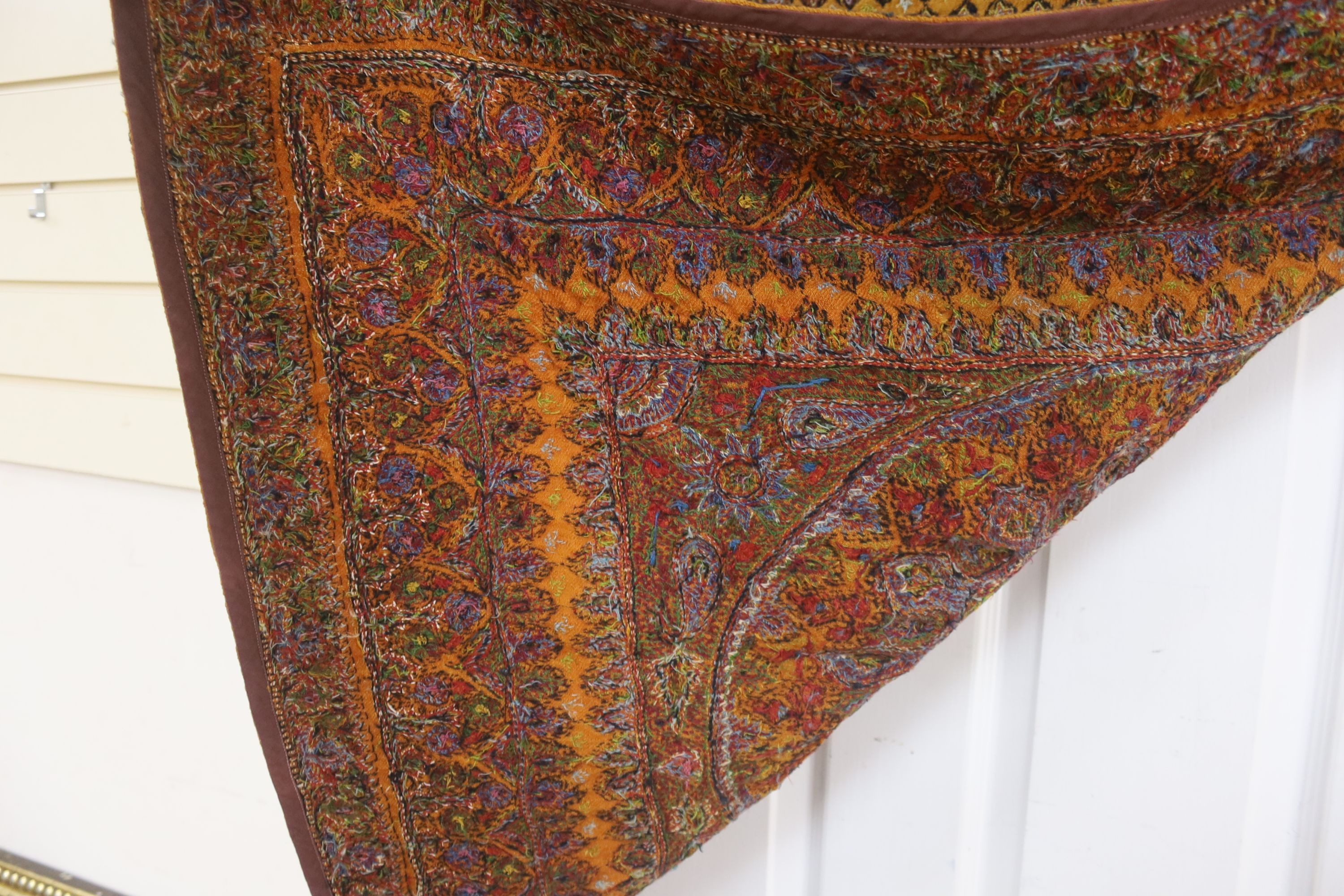 A Kashmiri wool embroidered hanging, with central cartouche, 97 cms wide x 99 cms high.